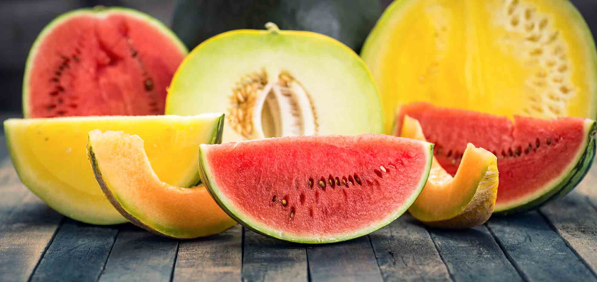 Watermelon, honeydew and canteloupe wedges and halves on wooden table pollen allergies