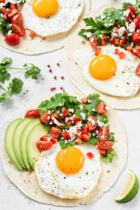 fried eggs on tortillas with avocado slices, diced tomatoes and cilantro egg allergies