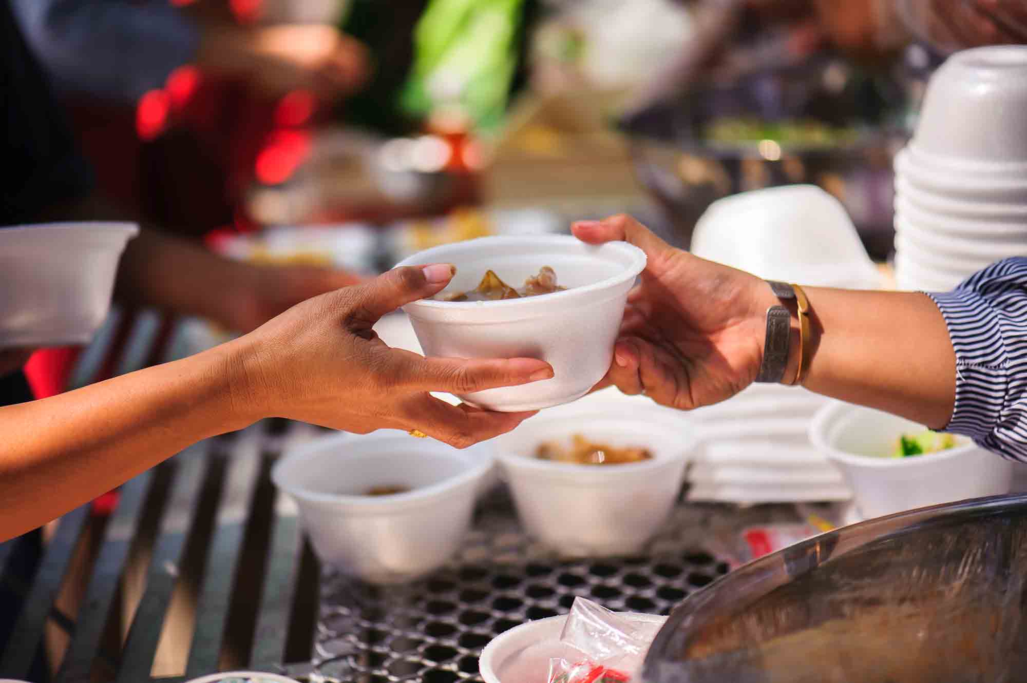 Distribute free food to the poor - two hands exchanging a bowl of food - basic human rights