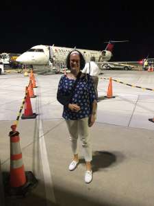 Tracy standing front of airplane with sling temporary disability