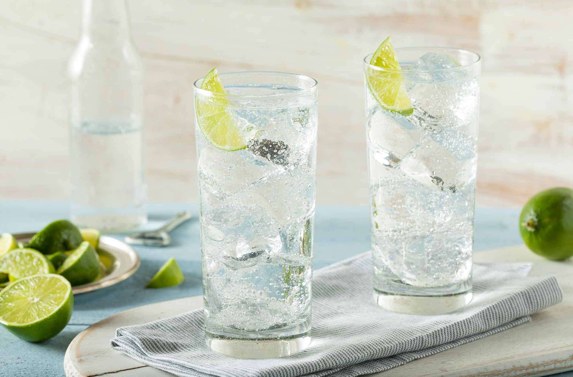Two clear glasses of Hard Sparkling Water with limes on a tray Drynuary