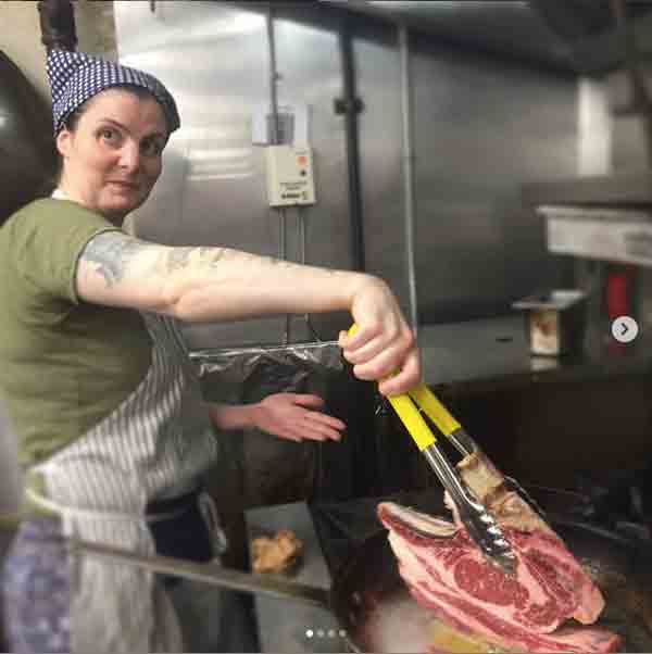 Aimee Francaes holding tongs with a steak on the grill