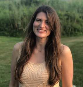 Young smiling woman standing outside wearing a sleeveless yellow top Allie Bahn teaches how to travel confidently with food allergies