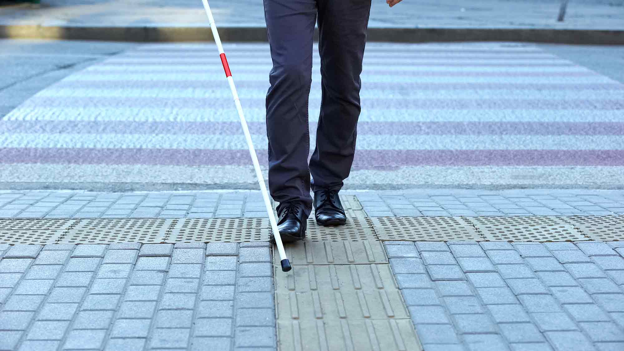 Visually impaired man using tactile tiles to navigate city, finishing crossroad Disability diplomat