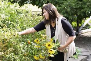 Smiling woman picking sunflowers. Loree Mulay Weisman makes allergen-free sausage