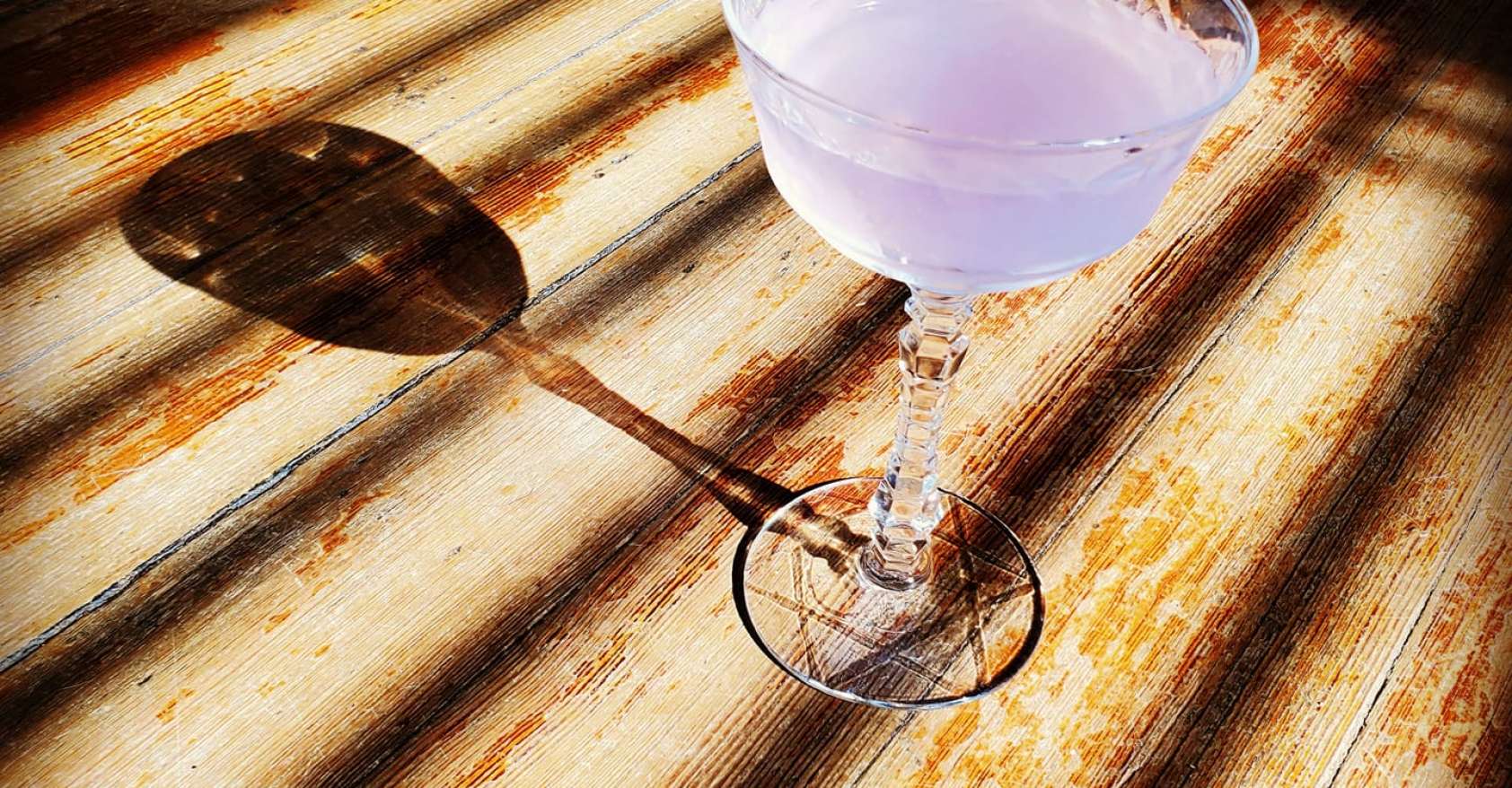 A single cocktail on a wooden deck its shadow to the left made by bartender Tiffanie Barriere who provides history lessons with every cocktail she serves