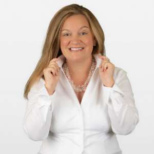 Smiling woman in a white shirt holding her collar out. She is a water sommelier