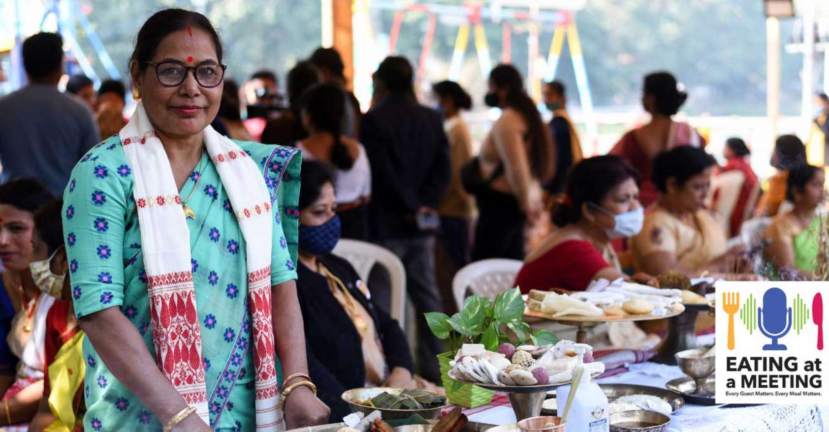 Indian woman standing behind a table of food showcasing the culture and community of eating together