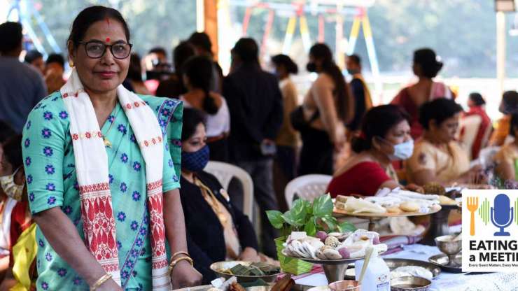 Indian woman standing behind a table of food showcasing the culture and community of eating together
