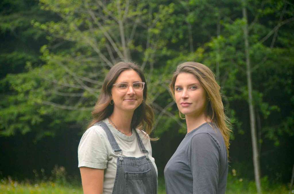 Two smiling women facing each other standing outside