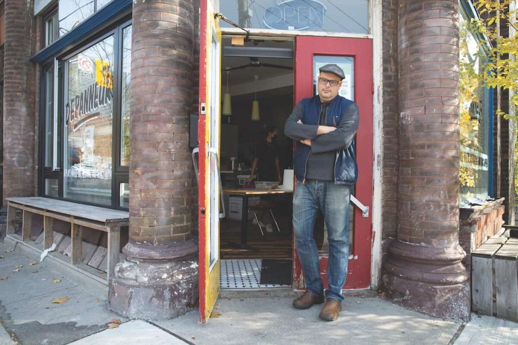 Len Senater standing in front of a red door, which is entrance to his restaurant