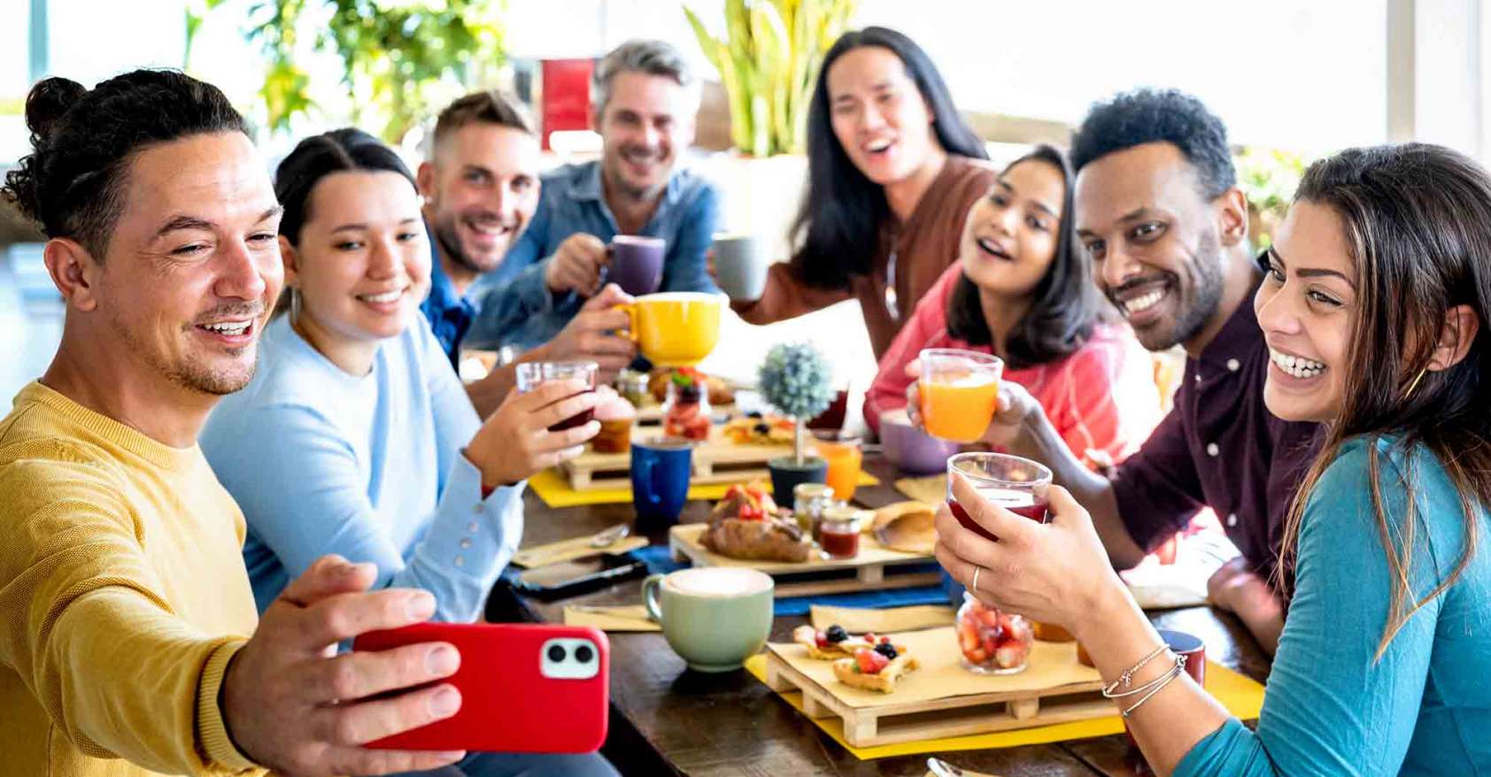 Friends taking selfie on breakfast time drinking juices and eating cakes - People having fun at fashion cafeteria - Life style concept with happy men and women at cafe bar equal eats