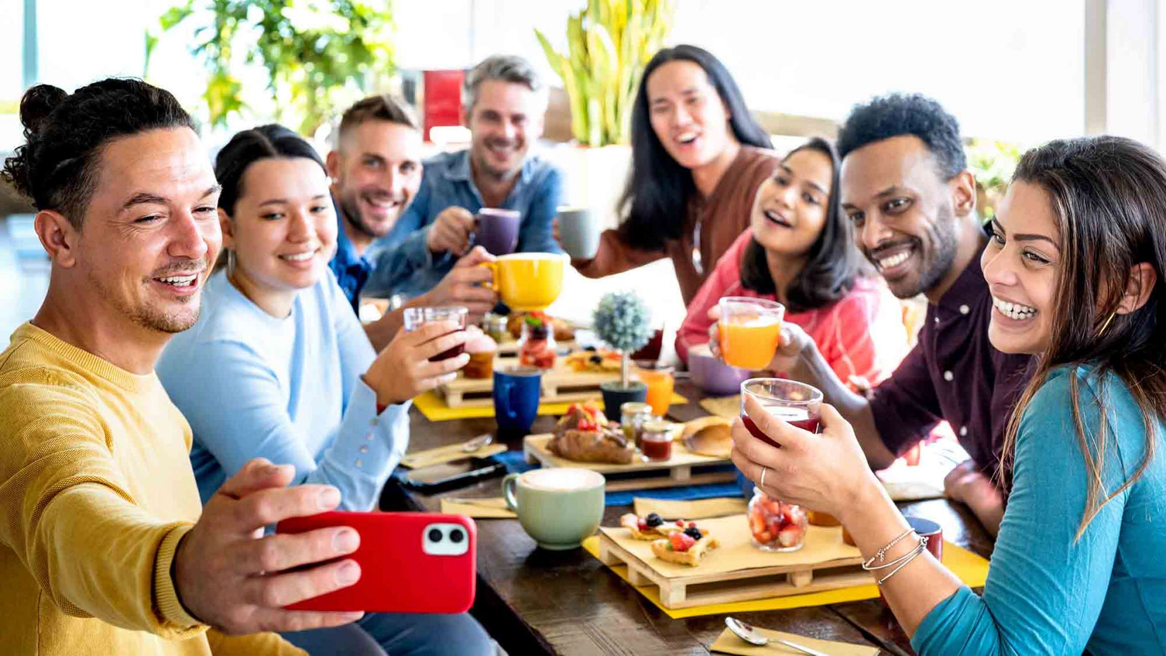 Friends taking selfie on breakfast time drinking juices and eating cakes - People having fun at fashion cafeteria - Life style concept with happy men and women at cafe bar equal eats