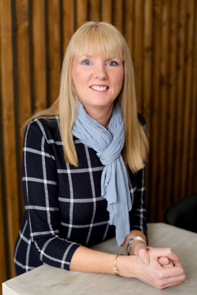 smiling woman with long blond hair wearing a navy blue suit. She teaches confidence around food allergies