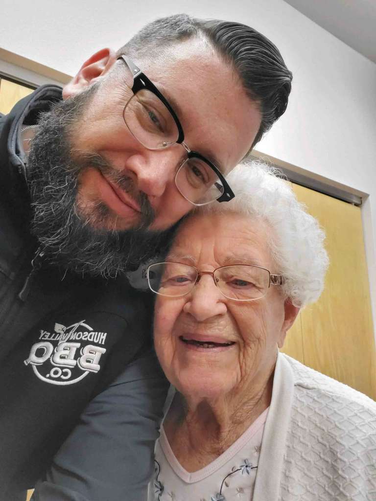 Man with brown hair and full beard leaning in to take a selfie with his grandmother. Brandon Snooks Farm to Fire