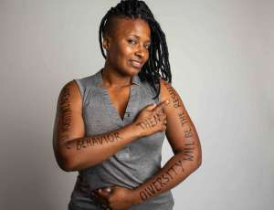 Woman pointing to the message written on her left arm.