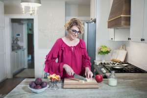Woman in pink top standing in kitchen dicing food on cutting board teaching about eating healthy with diabetes