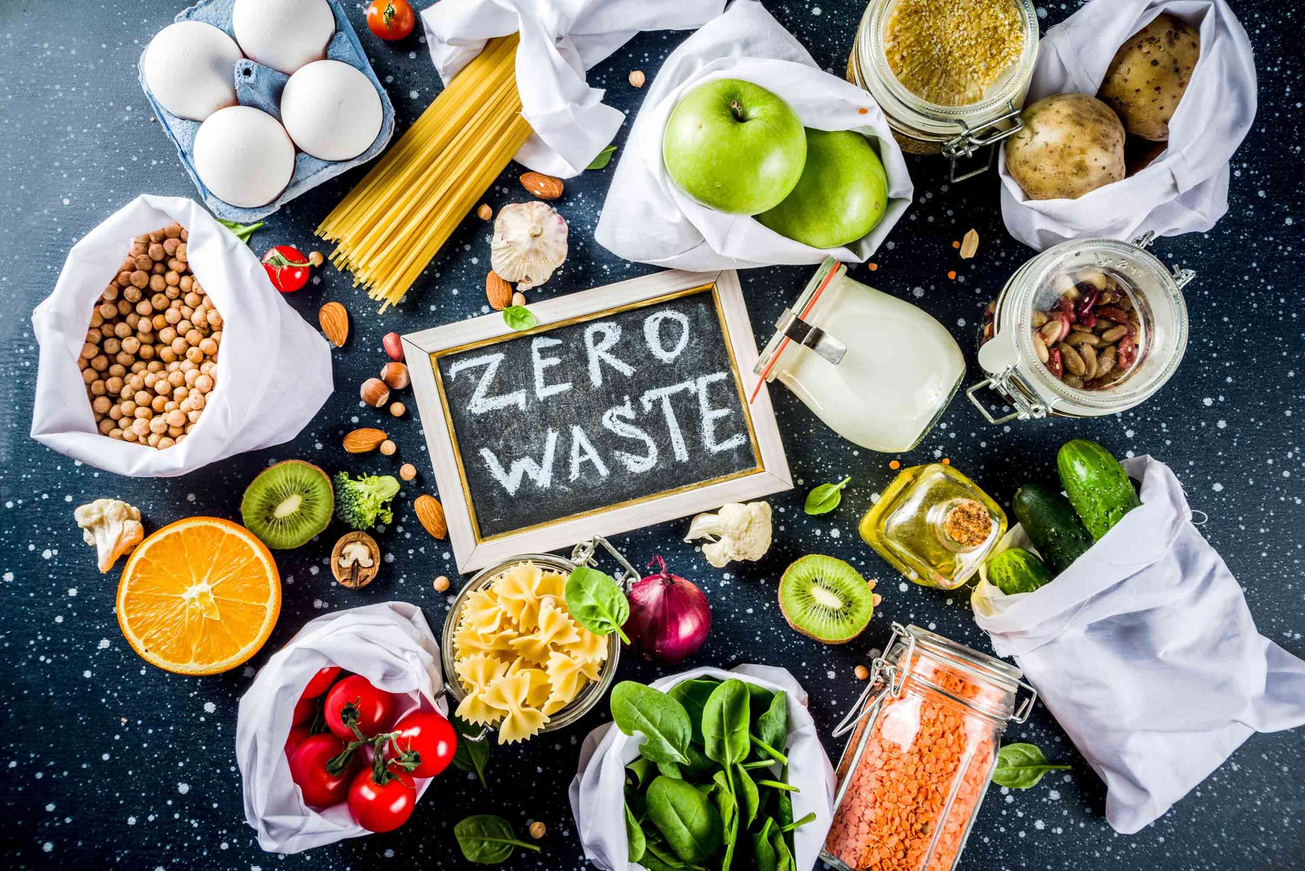 camera looking down on bags of food on a table with the words zero waste on a chalkboard in the center