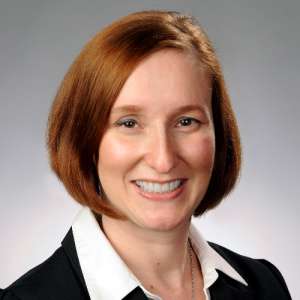Smiling woman with chin-length red hair. She is wearing a suit with a white blouse. Her name is Kristen Manion Taylor and she works for Delta Air Lines.