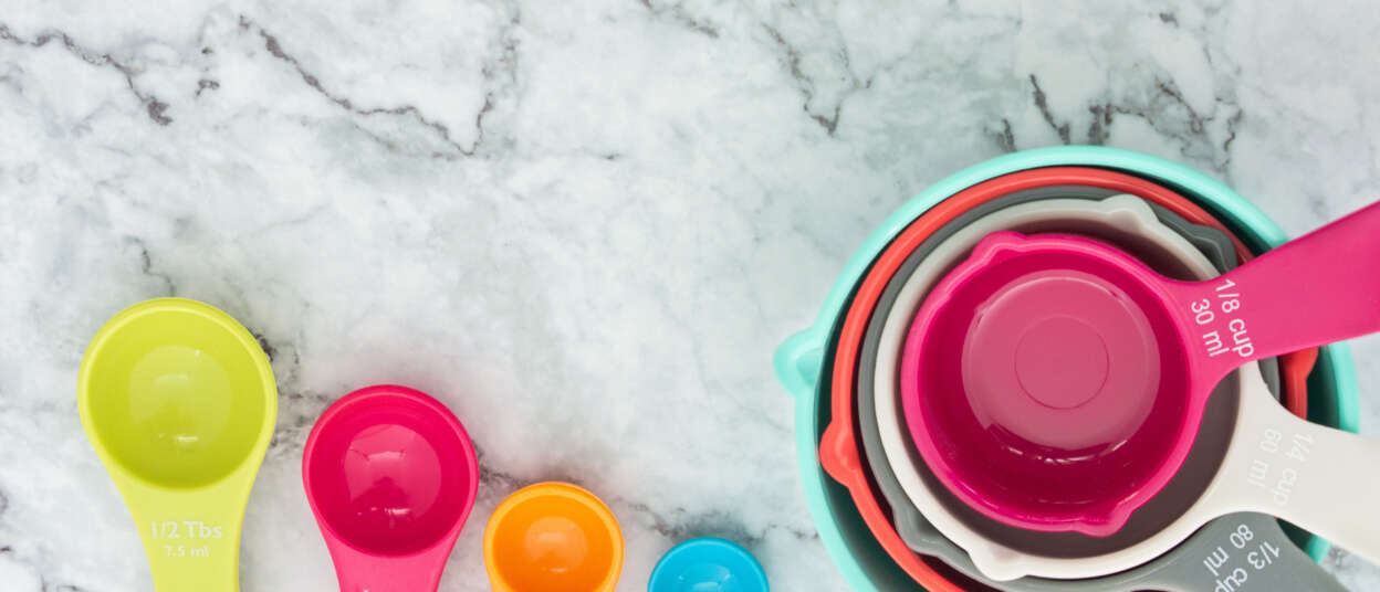 Set of colorful measuring cups and measuring spoons use in cooking lay on marble tabletop in top view. How do you measure F&B success?