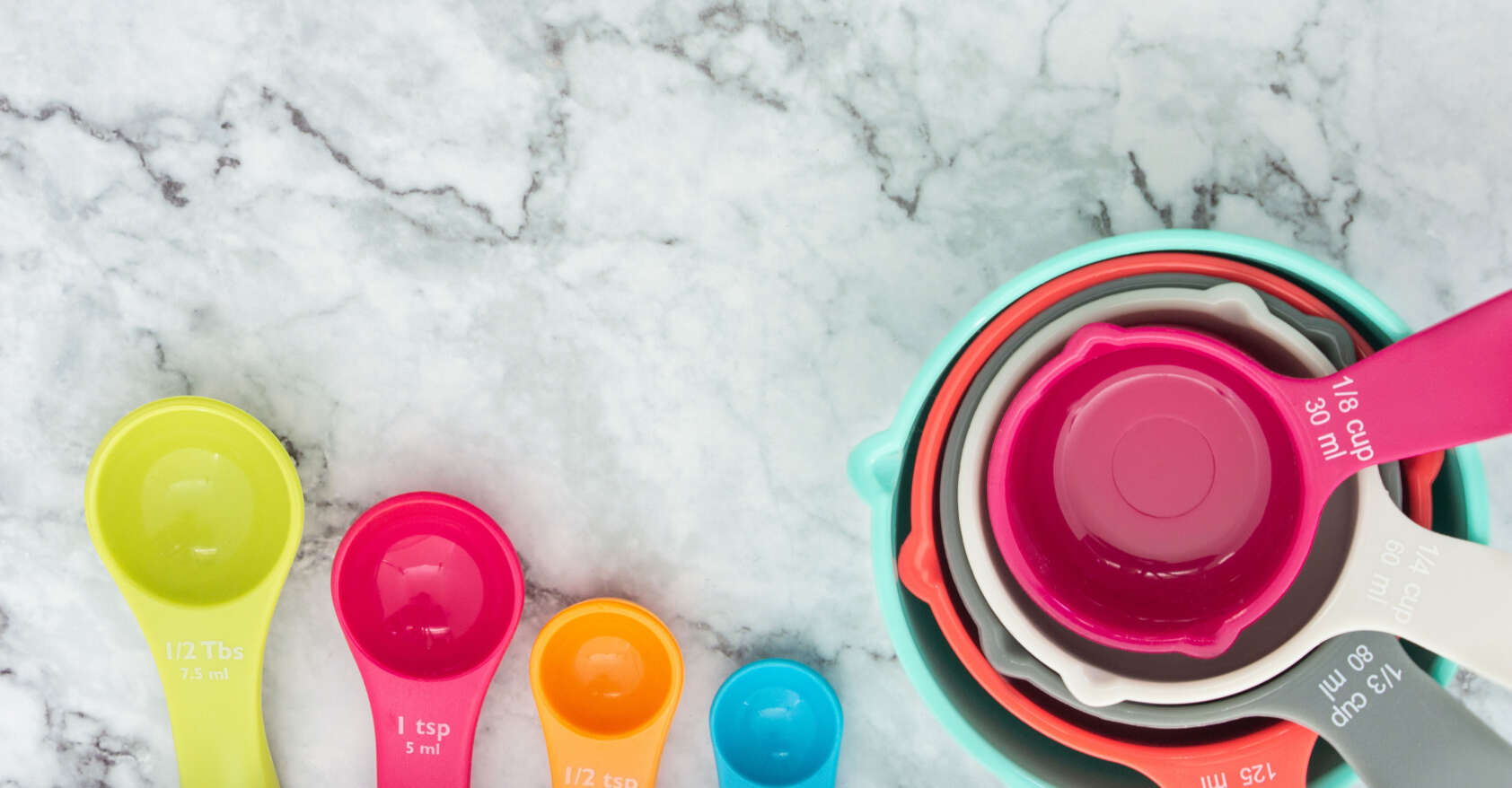 Set of colorful measuring cups and measuring spoons use in cooking lay on marble tabletop in top view. How do you measure F&B success?