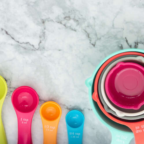 Set of colorful measuring cups and measuring spoons use in cooking lay on marble tabletop in top view. How do you measure F&B success?