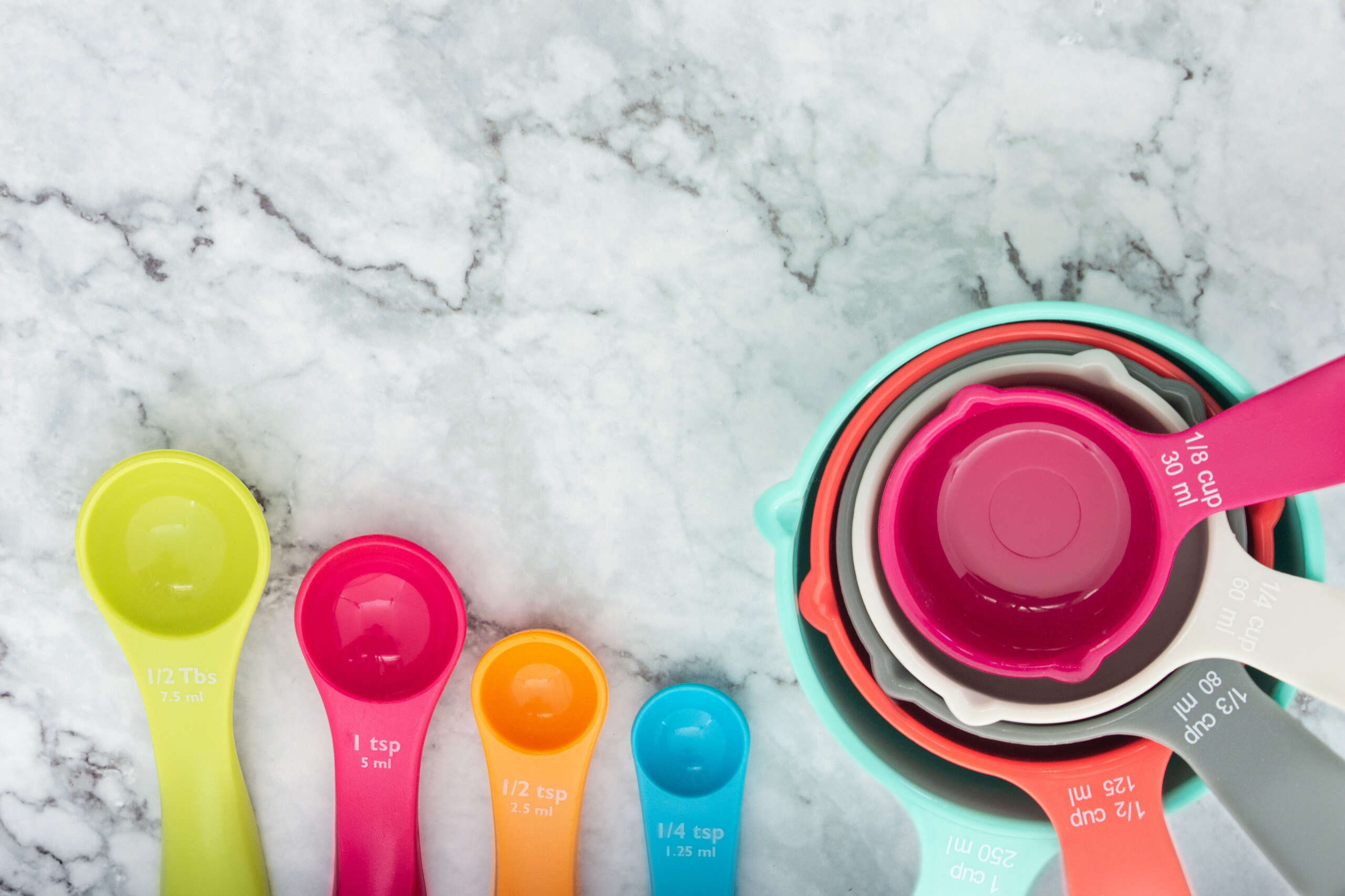 Set of colorful measuring cups and measuring spoons use in cooking lay on marble tabletop in top view. How do you measure F&B success?