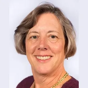 Smiling woman with short brown hair and highlights wearing a burgundy top.